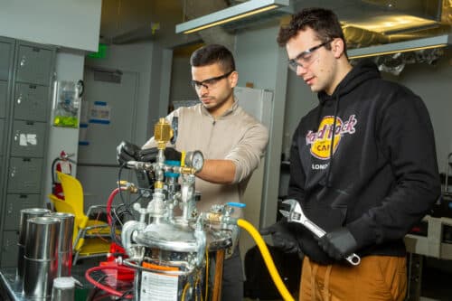 MIT engineers Aly Kombargi (left) and Niko Tsakiris (right) work on a new hydrogen reactor, designed to produce hydrogen gas by mixing aluminum pellets with seawater.
Credits:Photo: Tony Pulsone