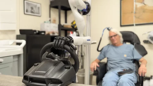 A testing participant controls a bionic hand through a brain-computer interface that allows him to feel pressure changes as the steering wheel moves in the hand. PC: University of Chicago